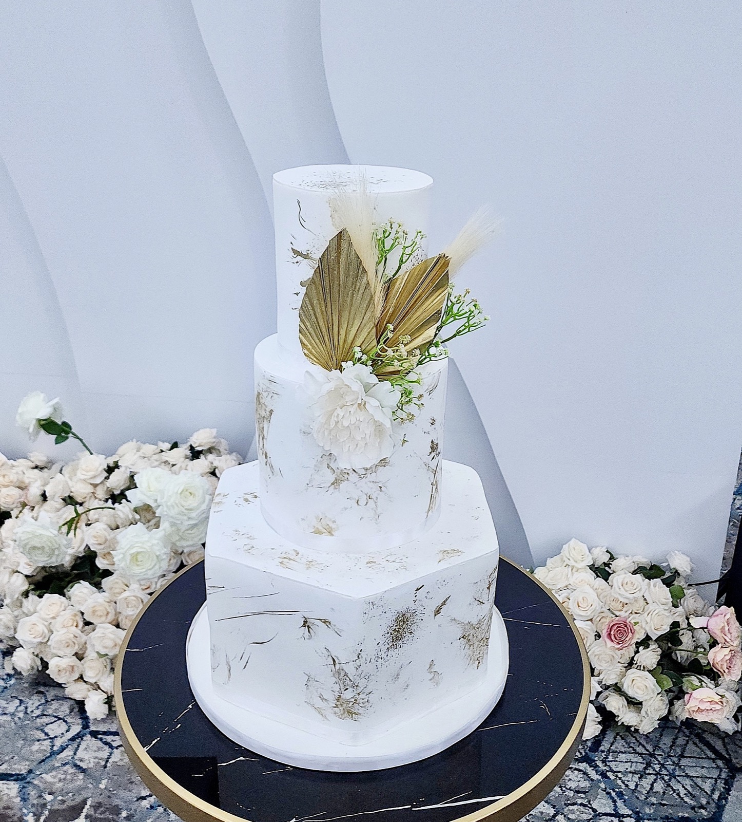 A refined white celebration cake with gold botanical details